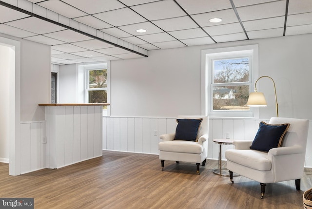 sitting room with wood-type flooring and a drop ceiling