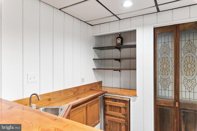 bar featuring sink, butcher block countertops, and a drop ceiling