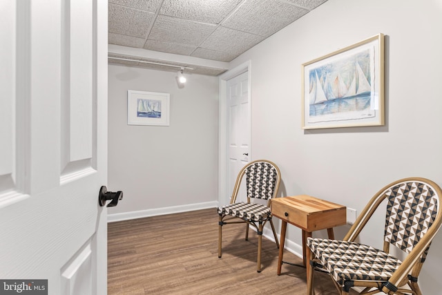 sitting room with a paneled ceiling and hardwood / wood-style floors