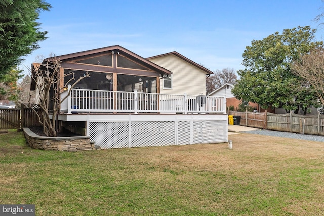 rear view of house with a wooden deck, a sunroom, and a lawn