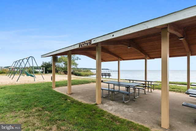 view of home's community featuring a playground, a water view, and a yard