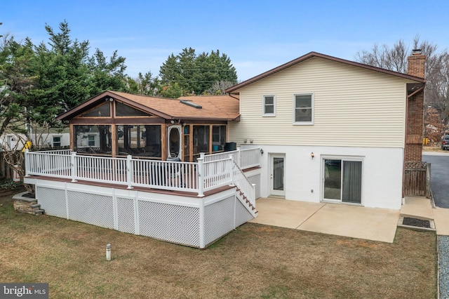 back of house with a sunroom, a deck, and a lawn