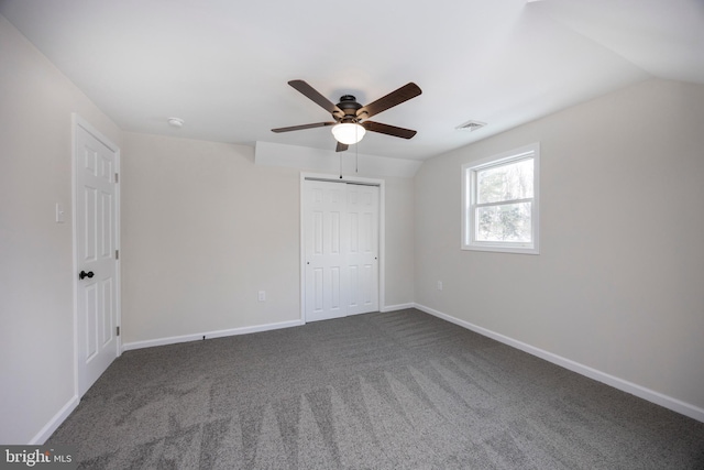 unfurnished bedroom featuring vaulted ceiling, a closet, ceiling fan, and dark colored carpet