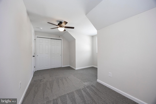 bonus room with ceiling fan and dark carpet