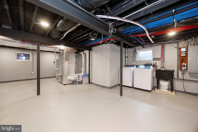 basement with heating unit, sink, washing machine and dryer, and electric panel