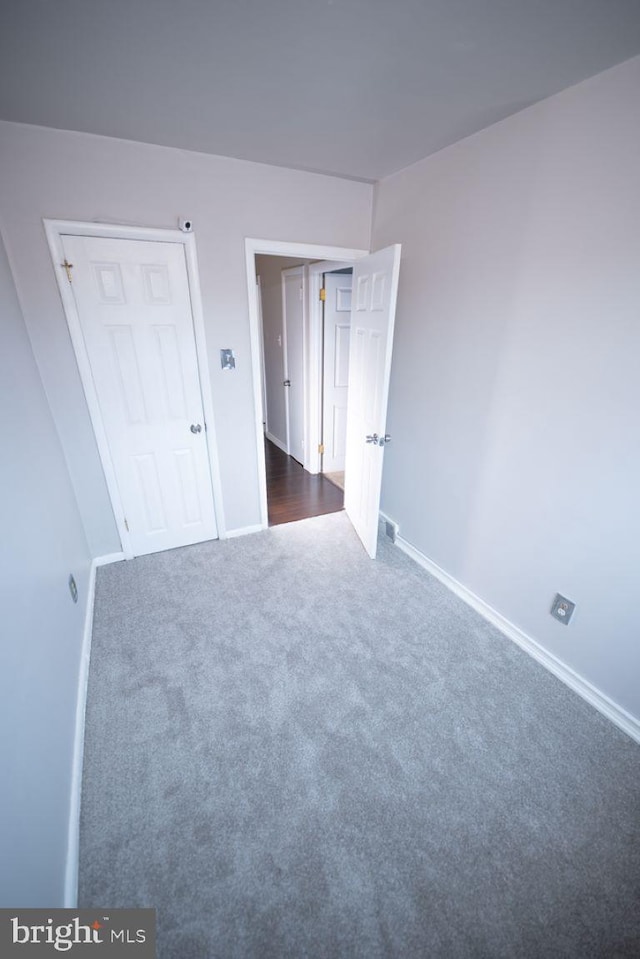 unfurnished bedroom featuring a closet and dark carpet