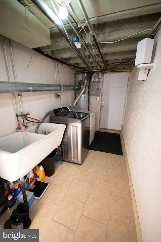 basement featuring water heater, light tile patterned floors, independent washer and dryer, electric panel, and sink