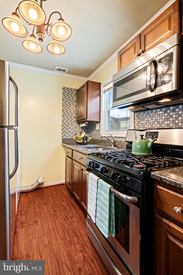 kitchen featuring stainless steel appliances, backsplash, dark hardwood / wood-style flooring, ornamental molding, and sink