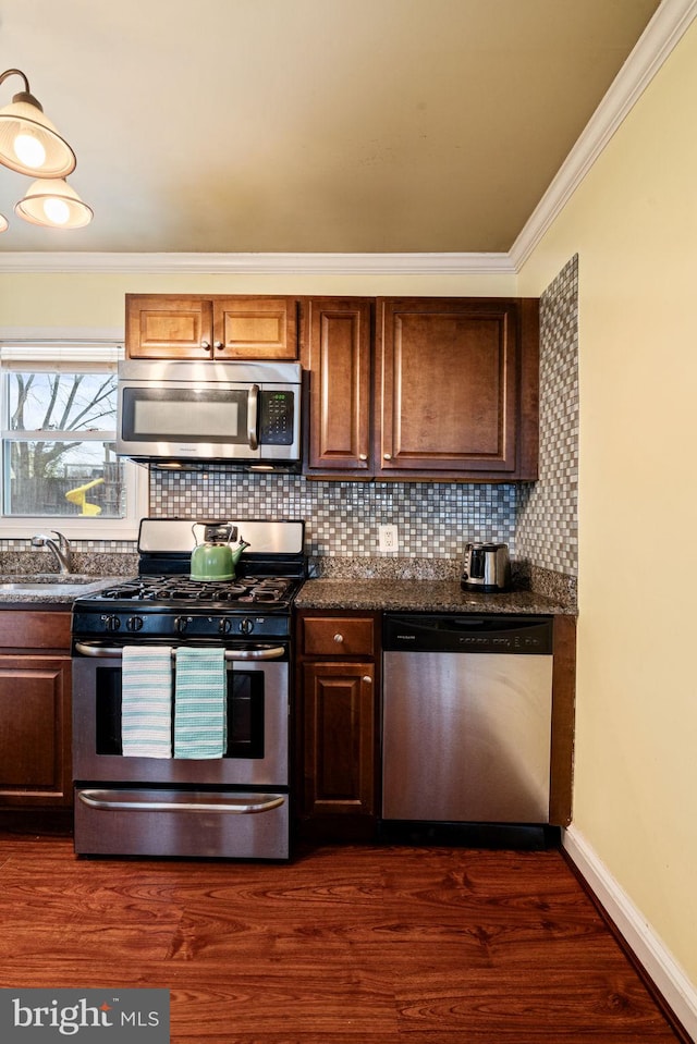 kitchen with dark wood-type flooring, appliances with stainless steel finishes, crown molding, and sink