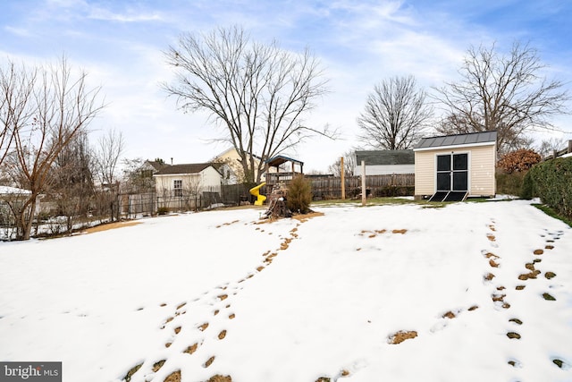 yard covered in snow with a playground and a shed