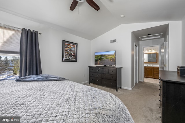 bedroom with vaulted ceiling, light carpet, ensuite bathroom, and ceiling fan