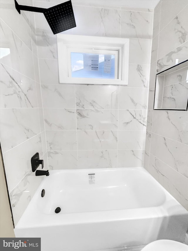 bathroom with tiled shower / bath combo and toilet