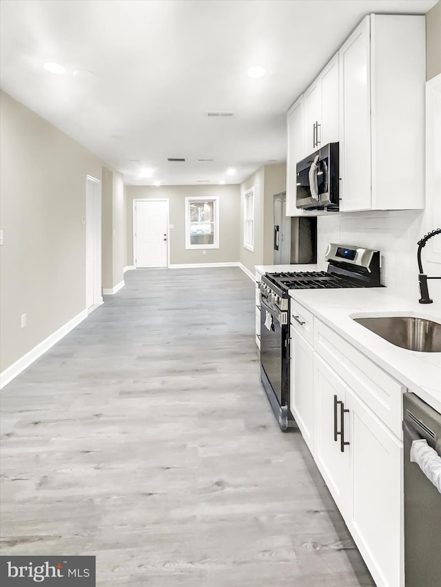 kitchen with sink, white cabinetry, light hardwood / wood-style flooring, and stainless steel appliances