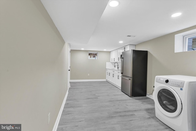 laundry area with light wood-type flooring, washer / clothes dryer, and sink