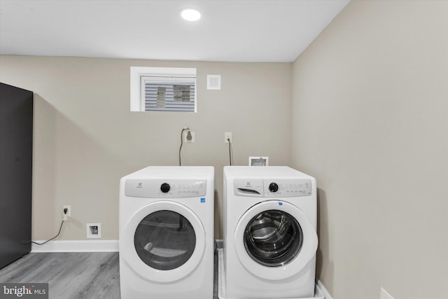 clothes washing area featuring light hardwood / wood-style flooring and washer and clothes dryer