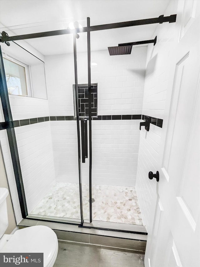 bathroom with toilet, concrete floors, and walk in shower