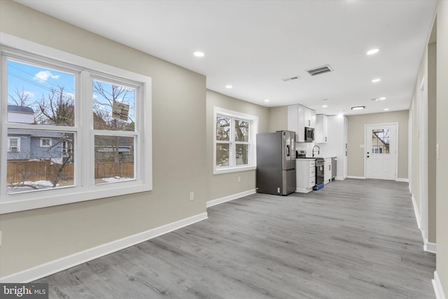 interior space featuring sink, white cabinets, stainless steel appliances, and light wood-type flooring