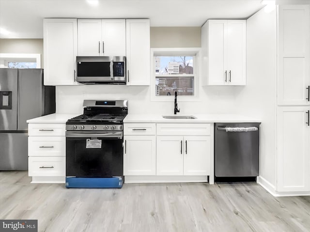 kitchen featuring sink, light hardwood / wood-style floors, white cabinetry, and appliances with stainless steel finishes