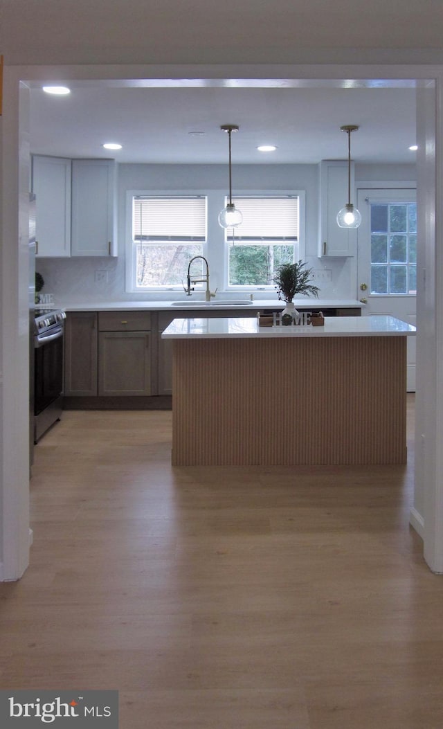 kitchen with white cabinets, decorative light fixtures, electric range, and light hardwood / wood-style floors