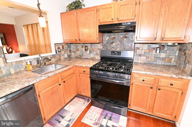 kitchen with appliances with stainless steel finishes, backsplash, decorative light fixtures, light stone counters, and sink