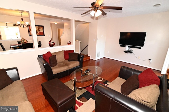 living room with a textured ceiling, ceiling fan with notable chandelier, and dark hardwood / wood-style floors