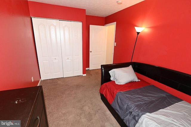 bedroom featuring a textured ceiling, a closet, and dark colored carpet