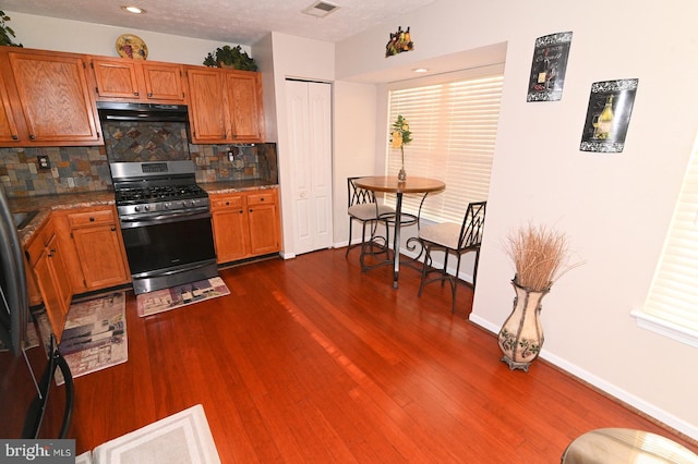 kitchen featuring a textured ceiling, dark hardwood / wood-style floors, backsplash, and stainless steel range with gas stovetop