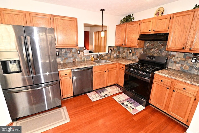 kitchen with stainless steel appliances, decorative backsplash, light stone counters, and sink