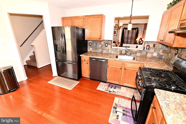 kitchen featuring hardwood / wood-style floors, decorative light fixtures, stainless steel appliances, sink, and backsplash