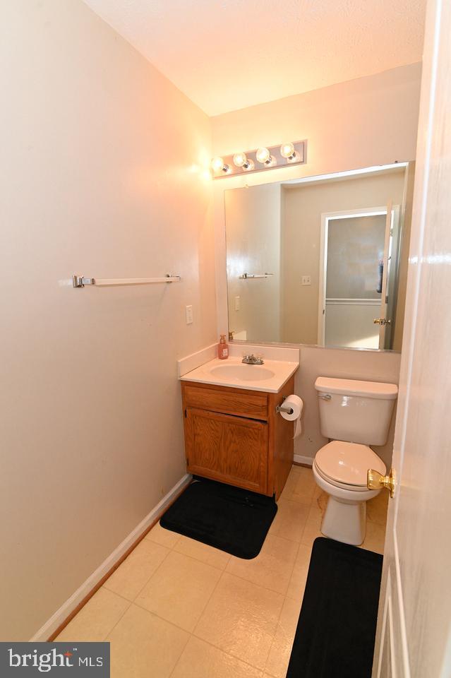 bathroom with toilet, tile patterned flooring, and vanity