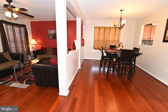 dining space with ceiling fan with notable chandelier and dark hardwood / wood-style flooring