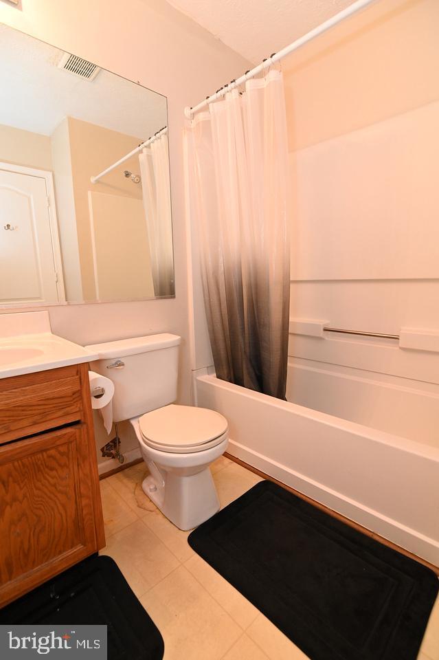 full bathroom featuring shower / bath combo with shower curtain, toilet, vanity, and tile patterned flooring