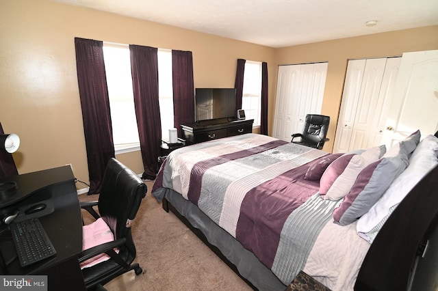 bedroom with light colored carpet and two closets