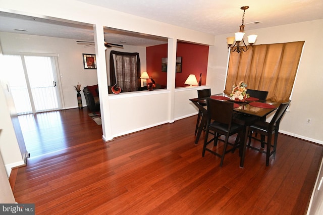 dining area with ceiling fan with notable chandelier and dark wood-type flooring