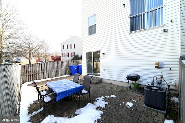 snow covered patio with central AC unit and area for grilling