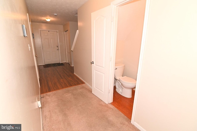 hallway featuring a textured ceiling and light carpet