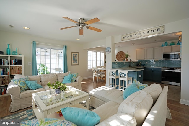 living room featuring ceiling fan, plenty of natural light, dark hardwood / wood-style floors, and sink