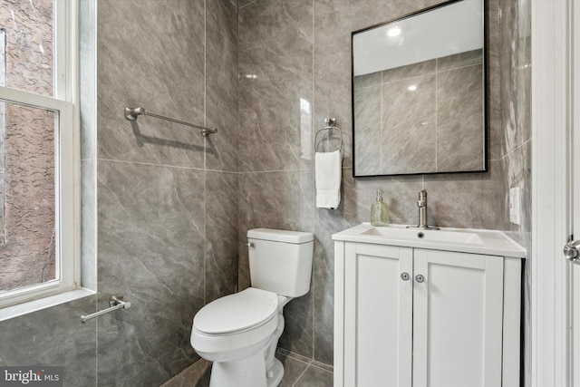 bathroom with vanity, tile walls, and toilet