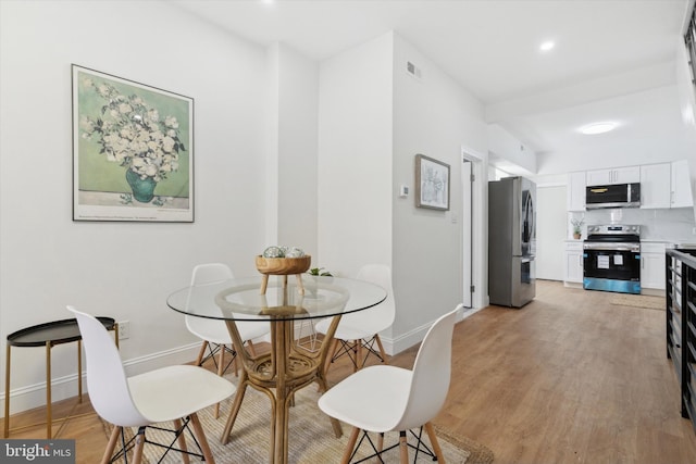 dining space featuring beam ceiling and light wood-type flooring