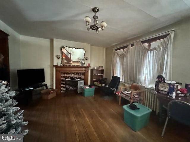 sitting room with a brick fireplace, hardwood / wood-style flooring, and an inviting chandelier