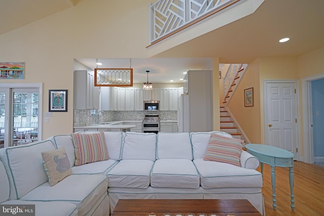 living room with hardwood / wood-style flooring, sink, and high vaulted ceiling