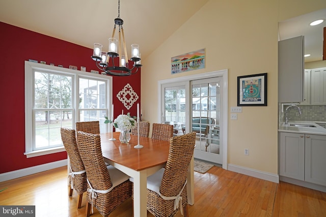 dining room with an inviting chandelier, a healthy amount of sunlight, sink, and light wood-type flooring