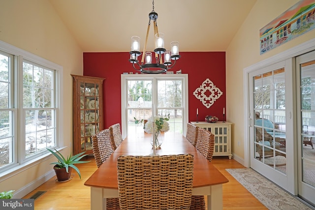 dining room featuring vaulted ceiling, wood-type flooring, and a notable chandelier