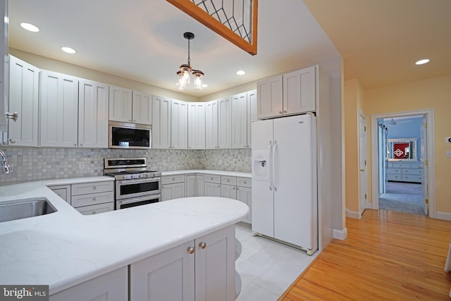 kitchen featuring sink, appliances with stainless steel finishes, hanging light fixtures, tasteful backsplash, and kitchen peninsula