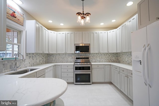 kitchen with tasteful backsplash, sink, decorative light fixtures, and stainless steel appliances