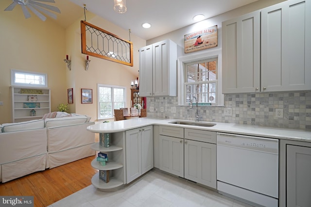 kitchen with gray cabinets, tasteful backsplash, dishwasher, sink, and kitchen peninsula