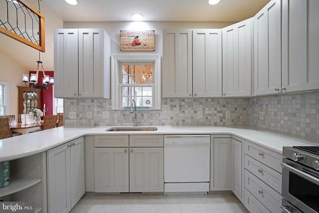 kitchen with sink, tasteful backsplash, white dishwasher, stainless steel stove, and pendant lighting