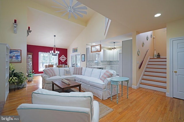 living room with an inviting chandelier, high vaulted ceiling, and light hardwood / wood-style floors