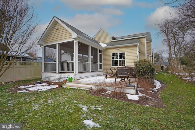 snow covered property featuring a patio, a hot tub, a sunroom, and a lawn