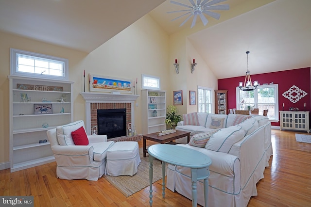 living room featuring an inviting chandelier, high vaulted ceiling, a fireplace, and light hardwood / wood-style floors